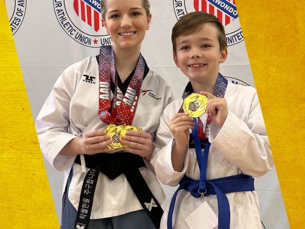 Two students holding up tournament medals they won.